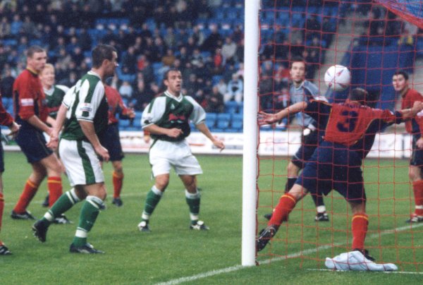 Goal! Adam Lockwood (far left) sees his header go goalbound despite the efforts of Gareth Hanmer to keep it out
